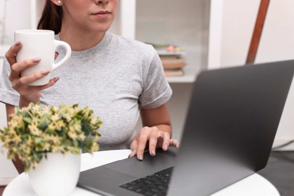 Image showing a woman with a cup of coffee looking at a computer.