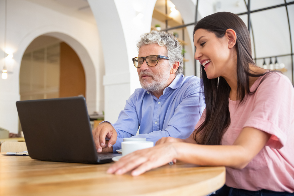 A young woman and an old man making a payment on a laptop.