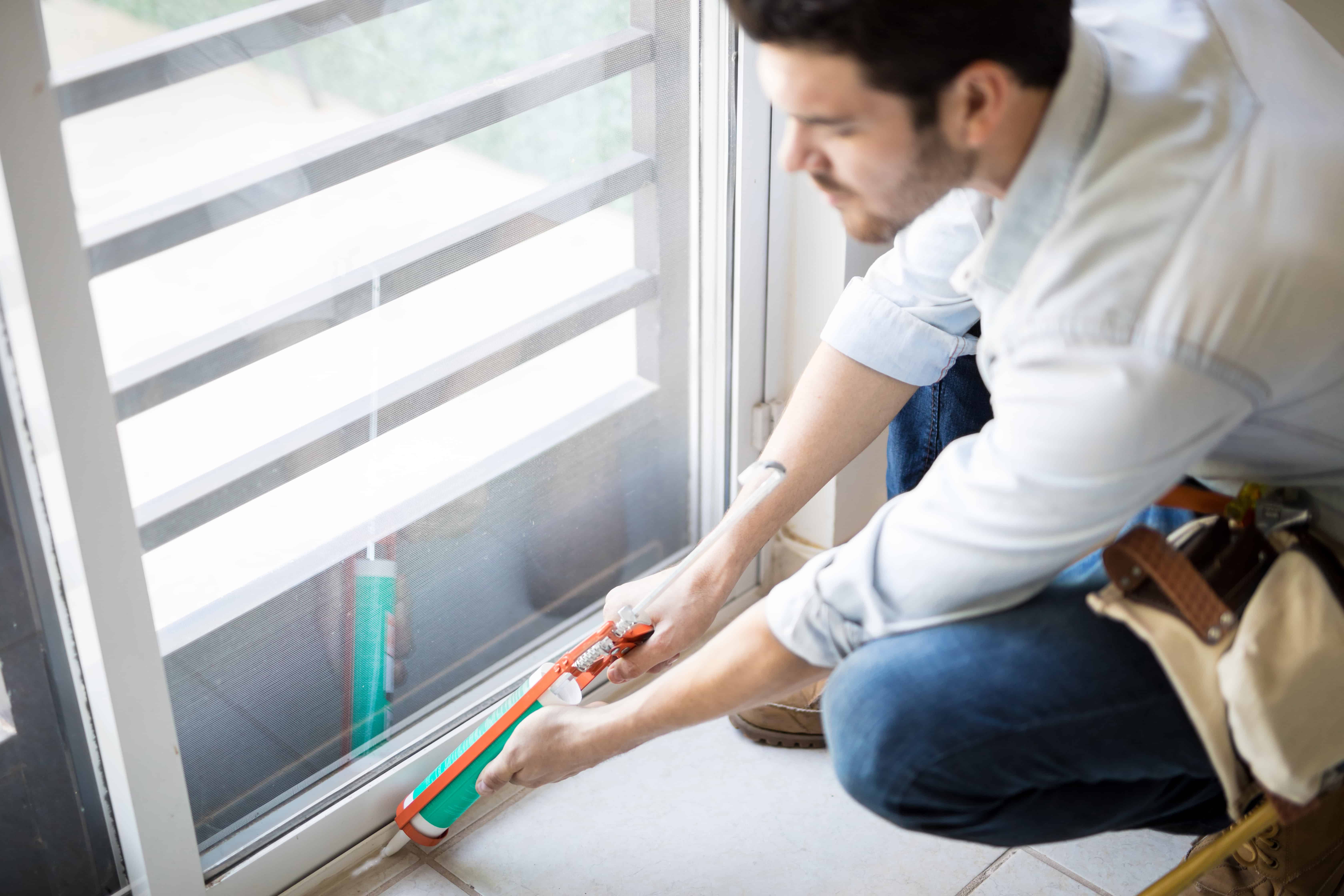 closeup-young-handyman-applying-some-sealant-door-with-sealing-gun-min