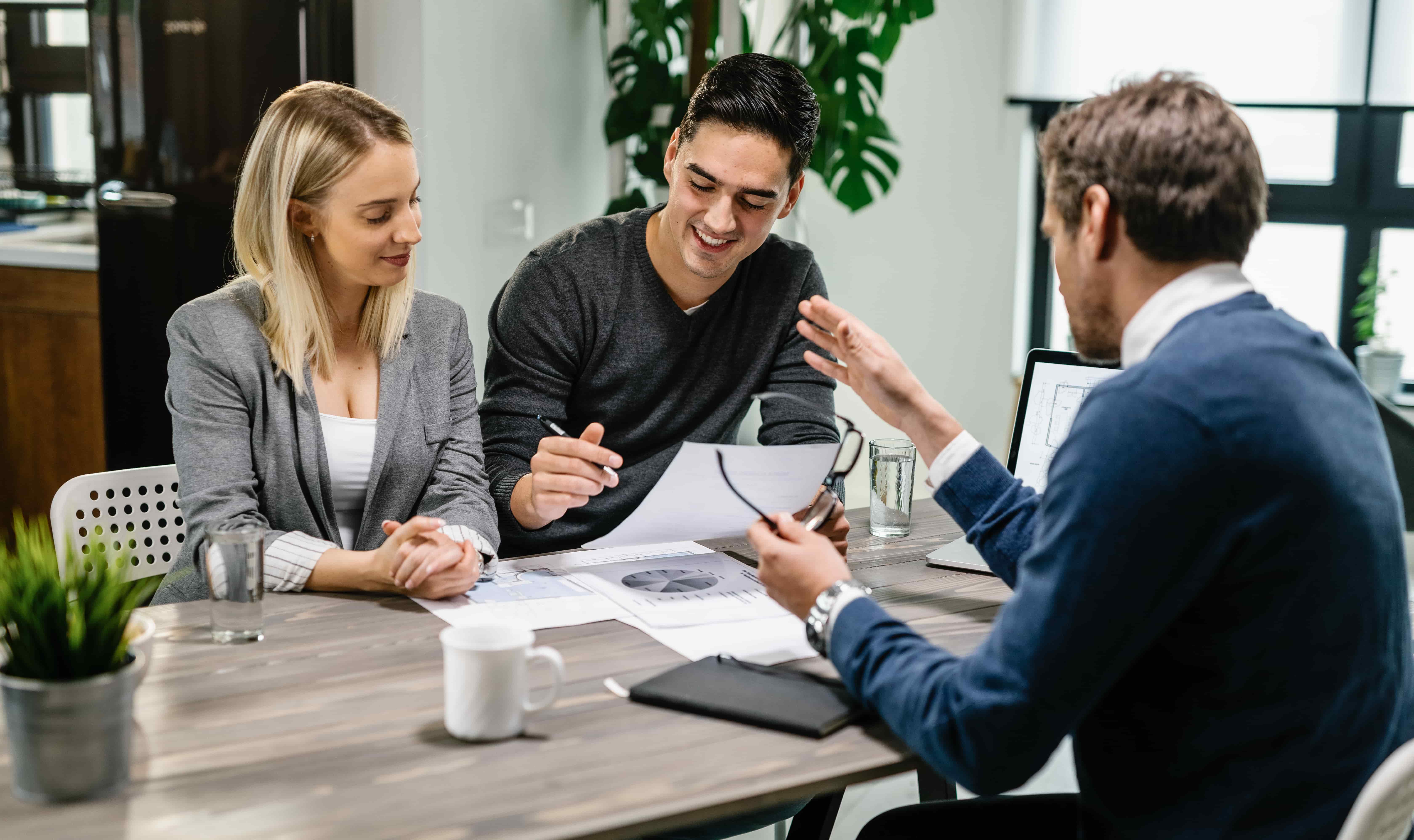 young-happy-couple-reading-terms-mortgage-documents-while-having-meeting-with-real-estate-agent-home-focus-is-young-man-min